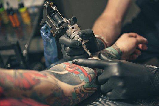 Tattoo artist using equipment to ink colorful tattoo on client's arm in studio